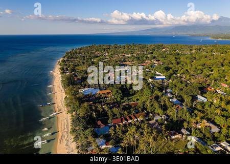 Vista aerea in droni della costa dell'isola di Gili Air, con spiaggia, barche e vegetazione lussureggiante Foto Stock