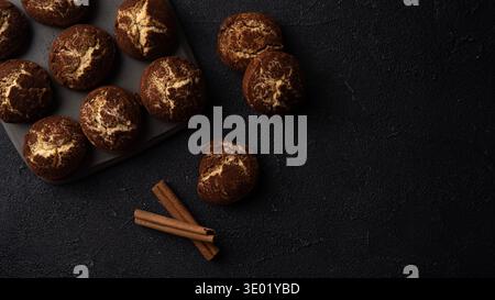 Biscotti alla cannella increspati su sfondo nero con spazio per le copie e disposizione piatta Foto Stock