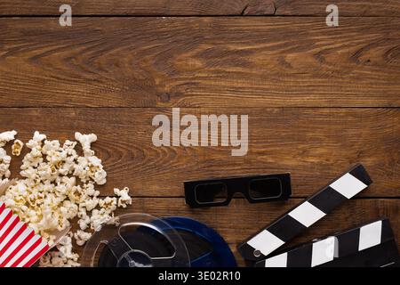 Tavoletta, bobina per pellicola e popcorn su sfondo in legno, vista dall'alto Foto Stock