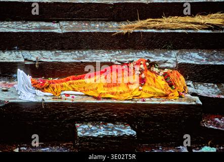 Le persone eseguono rituali di cremazione al tempio Pashupatinath di Kathmandu. Il corpo è posto sui gradini vicino al fiume per la cerimonia. Foto Stock