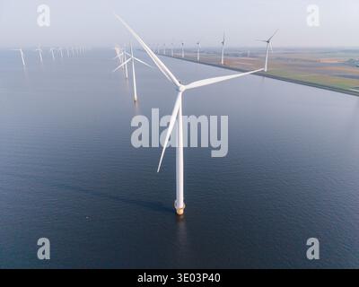 Una vista mozzafiato di un parco eolico offshore nei Paesi Bassi. Le turbine giganti sono alte, generano elettricità pulita e mostrano l'impegno del paese verso soluzioni energetiche sostenibili. Foto Stock