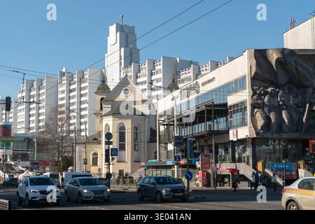 Minsk, Bielorussia - 8 marzo 2026: Intersezione della città su Pobediteley Avenue con grattacieli residenziali, piccola chiesa, semafori, automobili e. Foto Stock