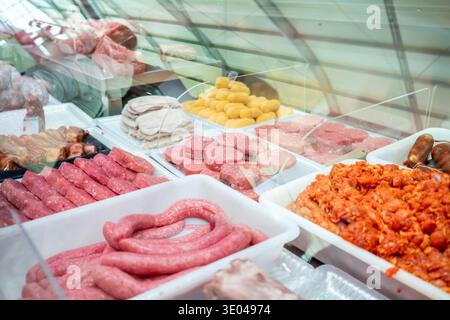 Una varietà di carni fresche è esposta in una macelleria. L'assortimento comprende salsicce, carne macinata e altri tagli, che mostrano l'artigianato del macellaio Foto Stock