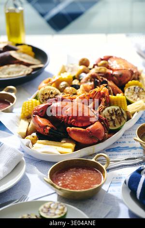 Un delizioso piatto di pesce con granchio intero, gamberi e crostacei, splendidamente disposti su un tavolo rustico. Ideale per cene in riva al mare e gourmet Foto Stock