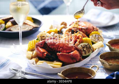 Un piatto gourmet di pesce con granchio intero, succulenti gamberi e crostacei assortiti. Perfetto per un pasto estivo in famiglia o per una cena in riva al mare Foto Stock