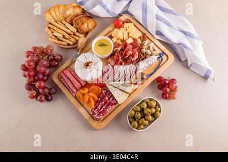 Un delizioso piatto di formaggi con una varietà di formaggi, affettati, uva fresca, frutta secca assortita e olive. Perfetto per riunioni eleganti e Foto Stock