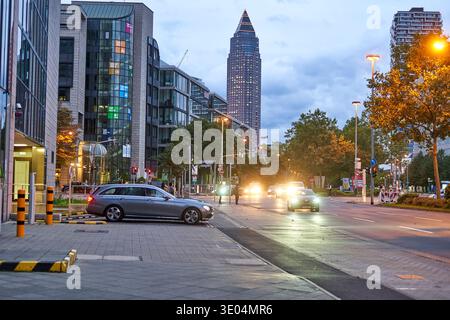 Scena serale urbana a Francoforte sul meno, in Germania, con l'iconico grattacielo Messeturm (Torre della Fiera) che si erge in primo piano nel... Foto Stock