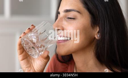 Donna sorridente che beve acqua fresca, immagine ravvicinata Foto Stock