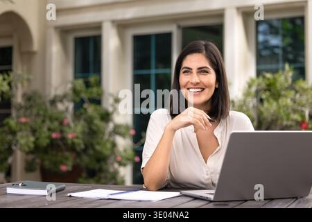 Donna professionale freelance felice che lavora dal giardino di casa Foto Stock