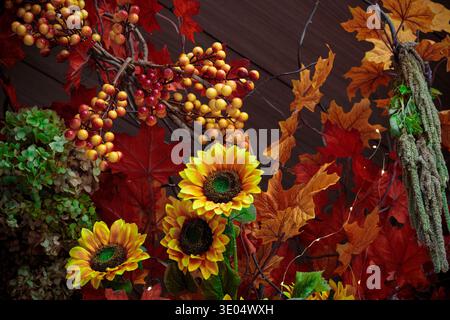 Un ricco arazzo di elementi stagionali, tra cui girasoli luminosi, bacche rosse e gialle e foglie d'acero colorate, evoca lo spirito dell'autunno Foto Stock