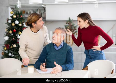I bambini adulti discutono tra loro e mostrano al loro padre maturo come compilare correttamente i documenti Foto Stock