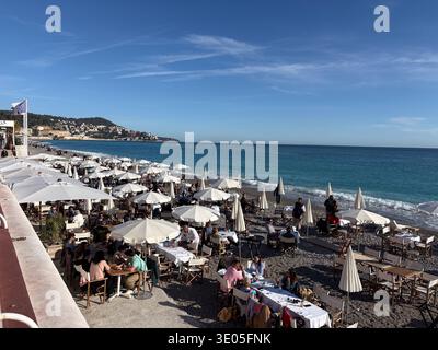Plage des Ponchettes. Ampia spiaggia di ciottoli con cena all'aperto, ombrelloni e vista sulla Baie des Anges a Nizza, Francia. Foto Stock