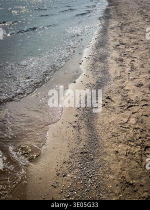 Vista prospettica lungo la costa dell'Ontario con onde dolci che scivolano su ciottoli e sabbia sul bordo dell'acqua, Canada Foto Stock