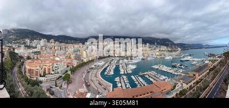 Vista di Port Hercule dal punto panoramico di Piazza del Palazzo, Monaco. Iconico panorama a volo d'uccello del porto d'acqua profonda, degli yacht di lusso e dello skyline di Monte Carlo sotto il c Foto Stock