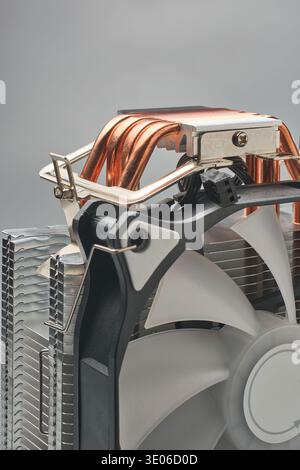 primo piano del refrigeratore di tipo tower cpu metallico sfondo grigio isolato, tubi di calore in rame esposti, alette in alluminio argento e pale della ventola in plastica nera Foto Stock