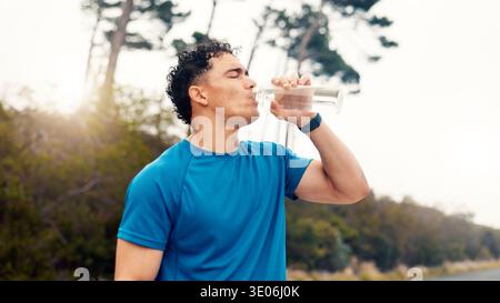 Uomo, fitness e bere con acqua in natura per l'idratazione, il riposo o il recupero dell'allenamento. Persona attiva, uomo o corridore con liquido minerale, acqua o. Foto Stock