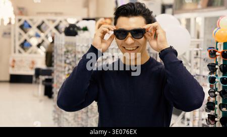 Uomo con maglione scuro che indossa o regola gli occhiali da sole Foto Stock