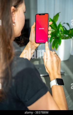 Praga, Repubblica Ceca - 19 febbraio 2026: Primo piano di una donna che tiene le mani sullo smartphone con l'app Tinder aperta sullo schermo. Interazione di incontri online e. Foto Stock