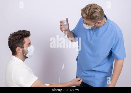 Medico di sesso maschile in uniforme blu che parla con un paziente Foto Stock