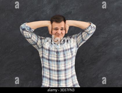 Uomo che si copre le orecchie con le mani e con le mani addosso Foto Stock