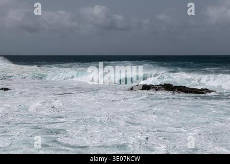 Le potenti onde dell'oceano Atlantico si infrangono contro le scure rocce vulcaniche lungo la costa frastagliata di El Cotillo, nelle Isole Canarie Fuerteventura, in Spagna, sono spettacolari Foto Stock