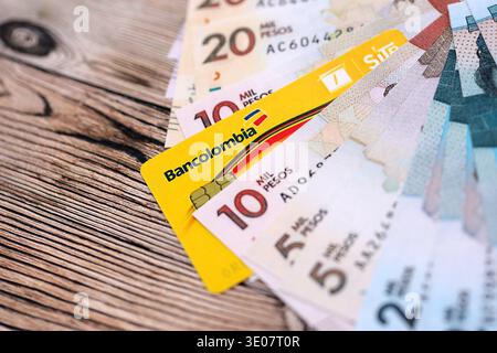 KIEV, UCRAINA - 28 GENNAIO 2026 Bancolombia card e banconote colombiane in peso sul tavolo da vicino. Bancolombia è la banca più popolare in Colombia Foto Stock