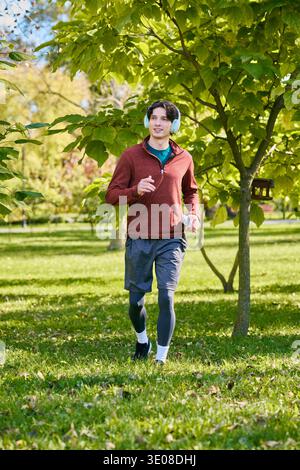 Un giovane con i capelli ricci si accarezza in un parco durante una bella giornata primaverile. Foto Stock