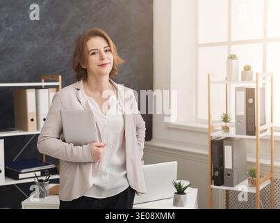 Donna d'affari sicura che tiene un tablet digitale sul posto di lavoro Foto Stock