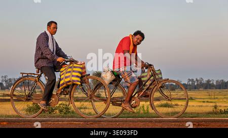 Uomini di ritorno da un mercato locale in bicicletta, Chhattisgarh, India Foto Stock