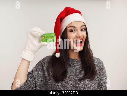 Donna felice nel cappello di babbo natale con carta di credito Foto Stock