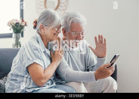 Felice coppia di famiglia in pensione utilizzando il telefono cellulare per videochiamare insieme, parlare con i rapporti, ottenere buone notizie, divertirsi, sorridere e ridere. Auto Foto Stock