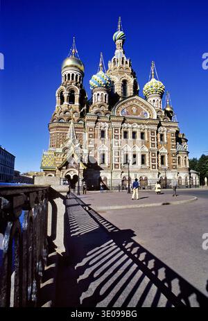 I visitatori camminano vicino alla Chiesa del Salvatore sul sangue versato a San Pietroburgo, in Russia, sotto un cielo azzurro. Foto Stock