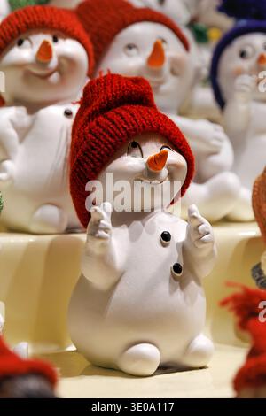 Graziosa statuina di pupazzo di neve con cappello rosso lavorato a maglia al mercatino di Natale Foto Stock