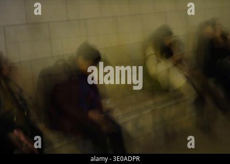 Fotografia sperimentale astratta e sfocata, lunga esposizione di pendolari che utilizzano smartphone sulla piattaforma della stazione della metropolitana di Monaco, Germania. Foto Stock