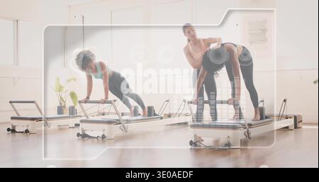 Istruttore leader che guida due clienti sui riformatori che fanno le tavole presso lo studio Pilates, indossando abbigliamento sportivo Foto Stock
