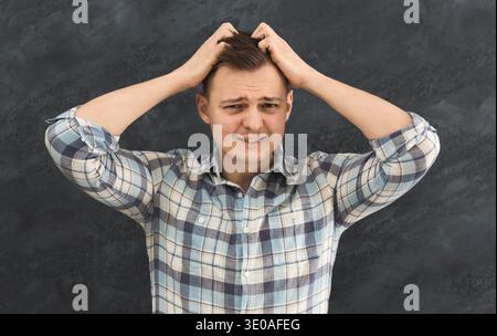 Giovane uomo disperato che tocca la testa Foto Stock