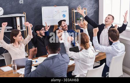 Giovani allegri che sembrano eccitati mentre sono seduti in ufficio Foto Stock