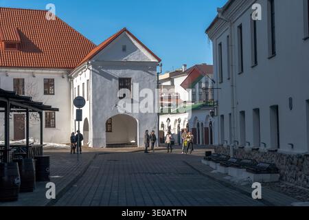 Minsk, Bielorussia - 8 marzo 2026: Edifici storici bianchi con tetti rossi e passaggi ad arco intorno alla piazza acciottolata nel quartiere della città vecchia di Minsk Foto Stock