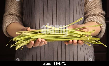 Donna in possesso di fettuccine di spinaci verdi crudi crudi Foto Stock