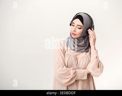 Una giovane donna in abbigliamento casual ascolta la musica con le cuffie mentre si rilassa a casa Foto Stock