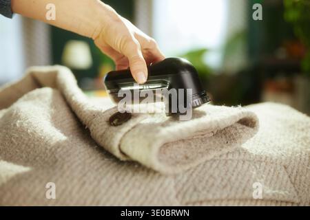 L'utilizzo di un rasoio elettrico in tessuto per rimuovere i pelucchi dal cappotto di lana è un passo fondamentale nella manutenzione stagionale dei capi e nella cura sostenibile del guardaroba. Foto Stock