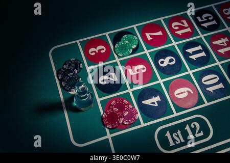 Pile di gettoni da poker collocati su un tavolo di roulette con un Dolly che segna una scommessa illustrano l'atmosfera del gioco d'azzardo Foto Stock