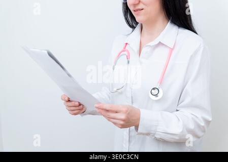 Medico donna con stetoscopio che legge il documento medico e rivede il referto del paziente, la consultazione sanitaria e il concetto di diagnosi medica in clinica Foto Stock