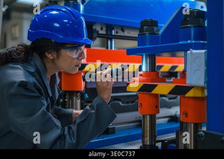 L'ingegnere industriale indiano conduce l'ispezione delle apparecchiature in un impianto di produzione per garantire il controllo di qualità e la sicurezza delle macchine. Foto Stock