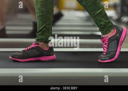 Primo piano delle gambe di una donna che cammina sul tapis roulant in palestra Foto Stock