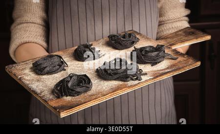 Chef donna con vassoio di legno con nidi di tagliatelle Foto Stock