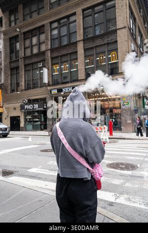 31.05.2025, USA, New York City, New York - Una scena di strada comica con una donna ad un passaggio pedonale nel centro di Manhattan di fronte alle nuvole di ste Foto Stock