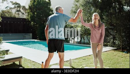 Fitness, coppia di cinque anni in giardino, sorridere e legarsi insieme per rapporto, umorismo o amore. Piscina, uomo anziano e donna felice Foto Stock