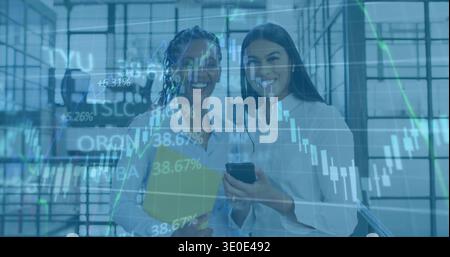 In piedi due donne in camicie leggere che tengono una cartella gialla e un telefono in una sala di vetro, sovrapposizioni finanziarie Foto Stock