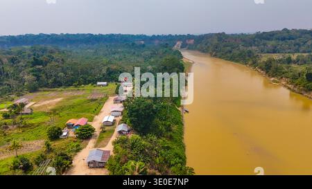 Vista aerea di un fiume fangoso che serpeggia attraverso la fitta foresta pluviale, con piccoli insediamenti annidati lungo le sue rive, Puerto Maldonado, madre de Dios, Perù. Foto Stock